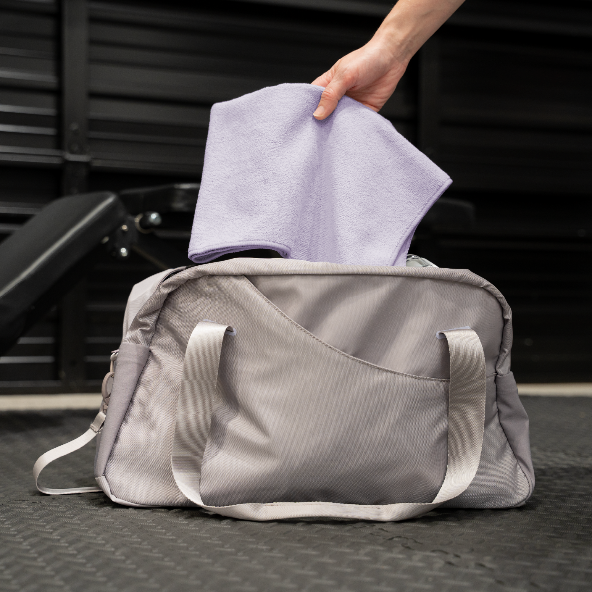 Person placing a purple gym towel into a duffel bag for on-the-go