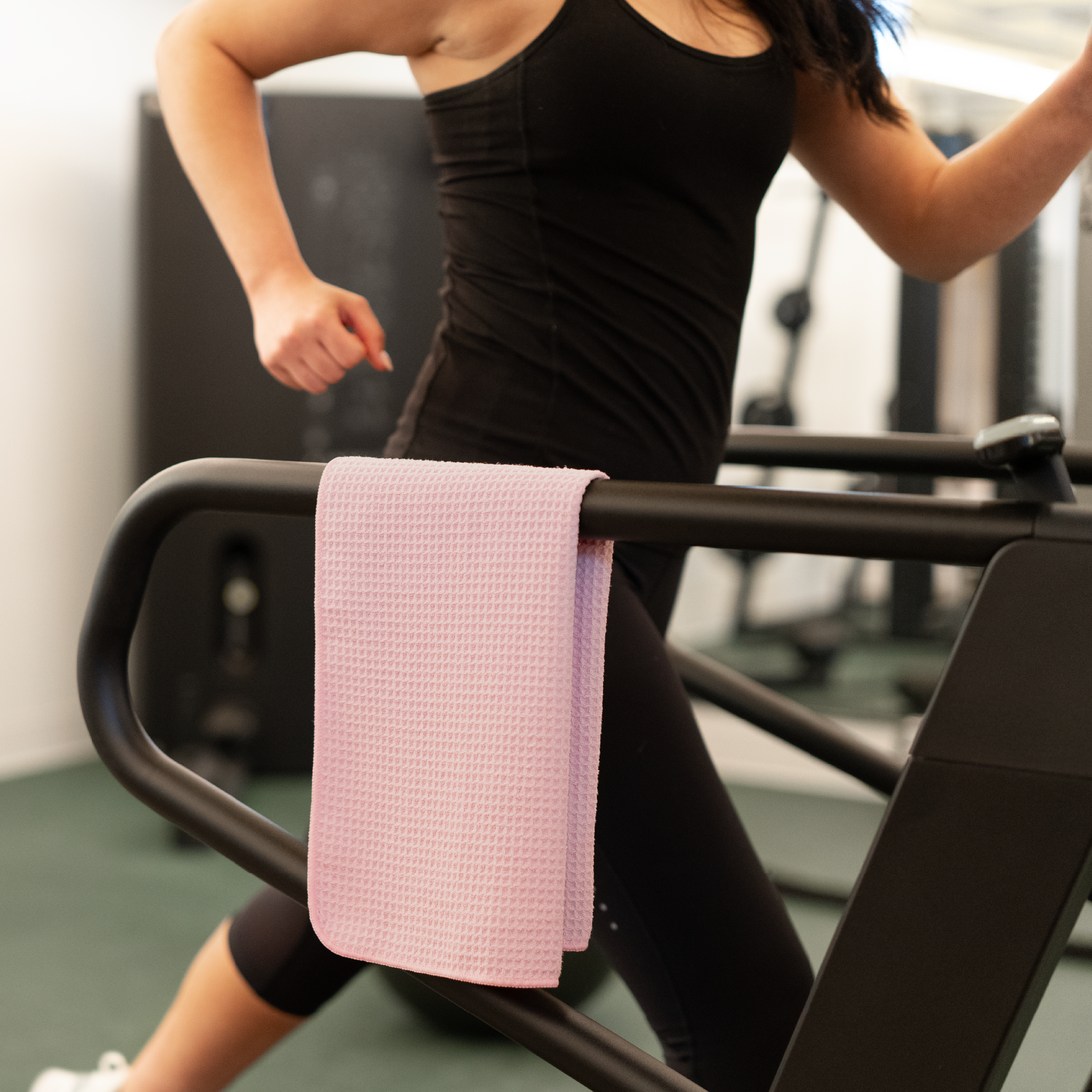 Person using a treadmill with a pink gym towel draped over the handle